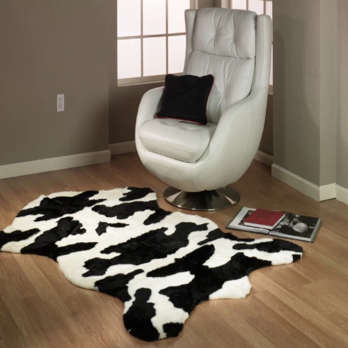 A dining room with a rustic wooden table and a colorful cowhide rug beneath