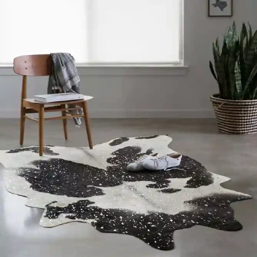 A black and white cowhide rug with silver accents placed on a gray concrete floor