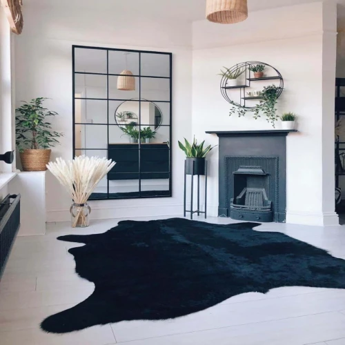 A black cowhide rug centered on a whitewashed floor in a modern living room