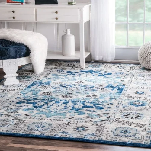 A blue and white Persian rug with a traditional design, placed on a wooden floor in a living room setting