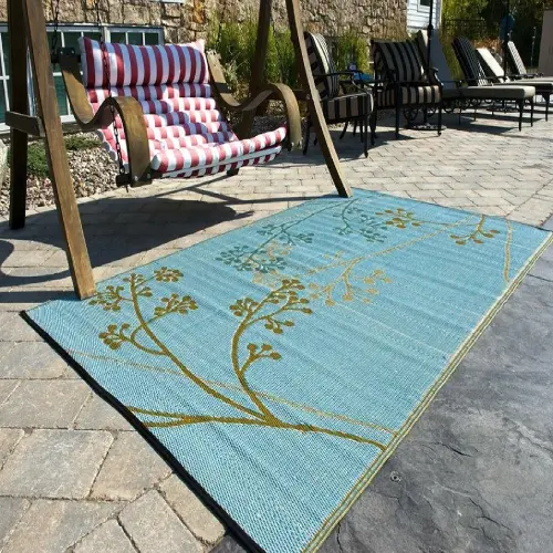 A blue outdoor rug with a tree branch design in gold