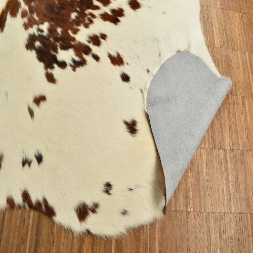 A close-up of a animal skin rug with a white base and brown spots.