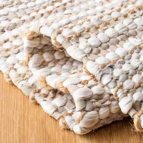 A close-up of a jute rug with a textured, knotted weave in shades of white and beige