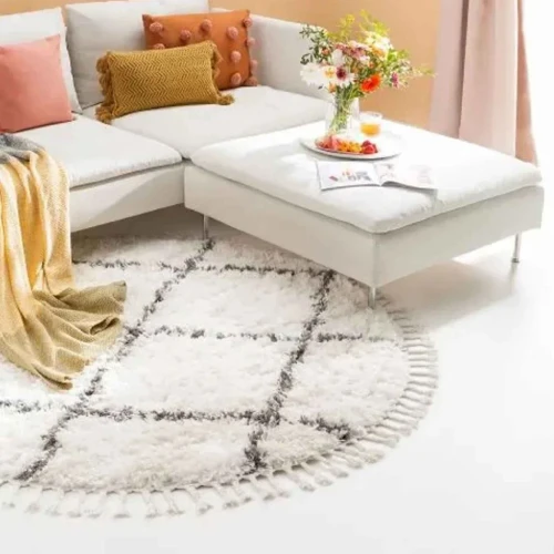 A close-up of a round rug with a diamond pattern and fringed edges