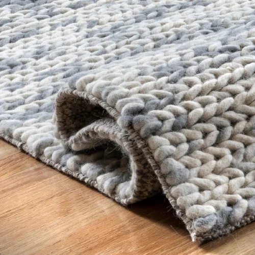 A close-up of a thick, textured wool rug in shades of gray and white