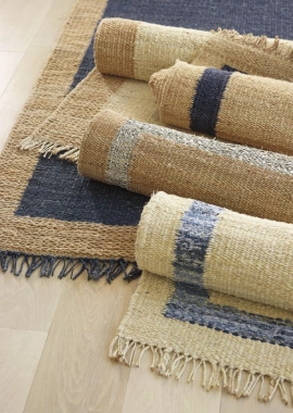 A collection of rolled-up jute rugs with blue and beige stripes and frayed edges