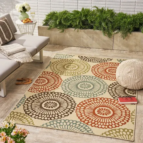 A colorful outdoor rug with a circular pattern is placed on a patio.