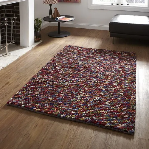 A colorful, textured wool rug with a pebble-like pattern in shades of red, orange, yellow, green, blue, and gray