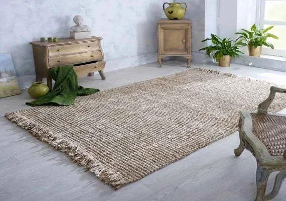 A large jute rug with a textured weave and fringed edges, placed in a living room with a wooden dresser,