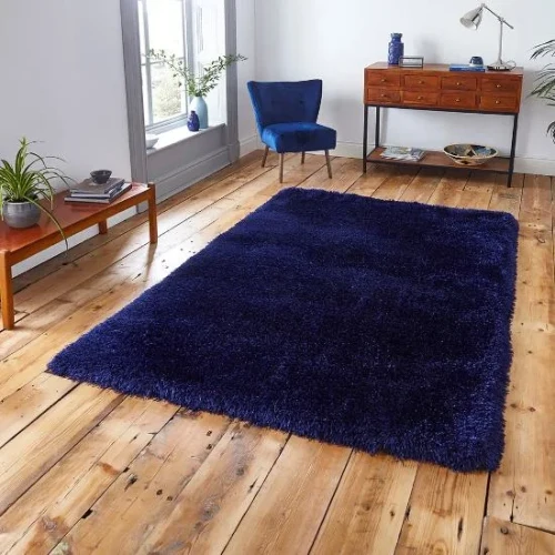 A large, shaggy navy blue rug placed in a living room with a wooden floor