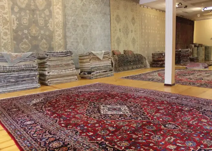 A large showroom filled with stacks of folded Persian rugs in various sizes and colors