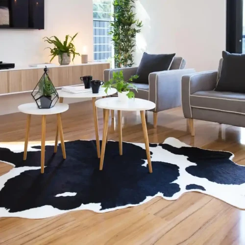 A modern living room featuring a black and white cowhide rug, a gray sofa