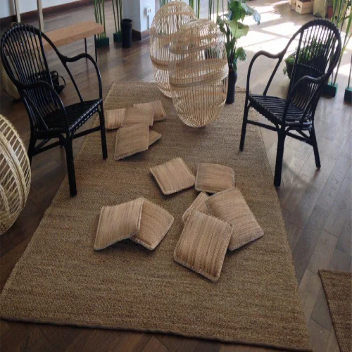 A modern living room featuring a large sisal rugs, rattan chairs, and woven pendant lights