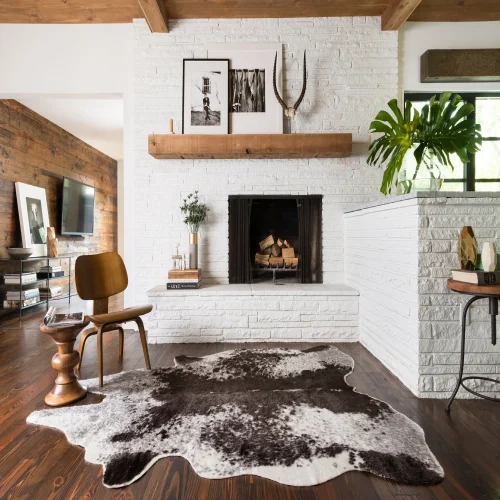 A modern living room featuring a white brick fireplace, a wooden mantle