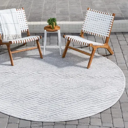 A round, gray outdoor rug with a chevron pattern is placed on a patio