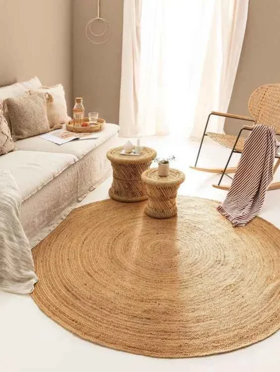 A round jute rug with a braided design, placed in a minimalist living room