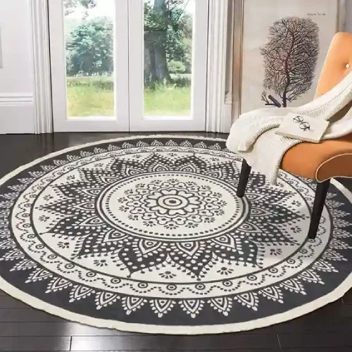 A round rug with a black and white mandala pattern in Dubai, placed under a chair with a blanket on it