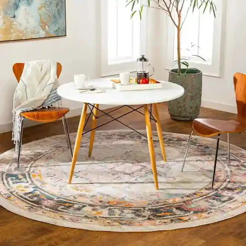 A round rug with a colorful abstract pattern in Dubai, placed under a round dining table with two chairs