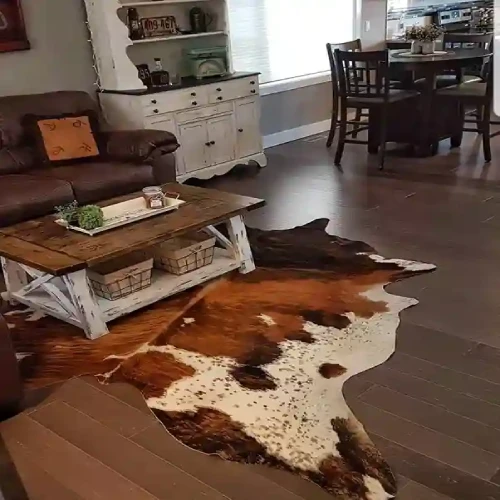 A rustic living room featuring a brown leather couch, a white distressed coffee table, and a large