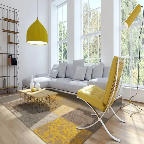 Modern living room in Dubai with a large gray sectional sofa, yellow armchair, and a patchwork rug in shades of beige