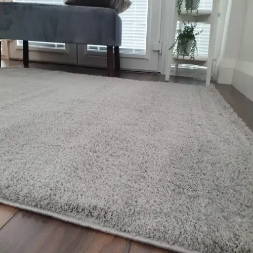 Soft shaggy light gray rug on a wooden floor