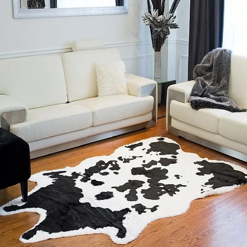 a black throw blanket, and a large black and white cowhide rug on the floor.