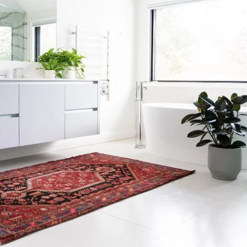 colorful Persian rug in shades of red and black is placed on the floor