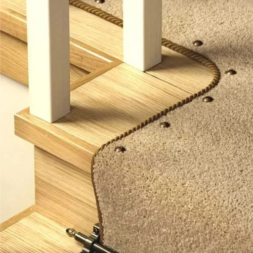 A beige stair carpet with a decorative edge trim and metal studs