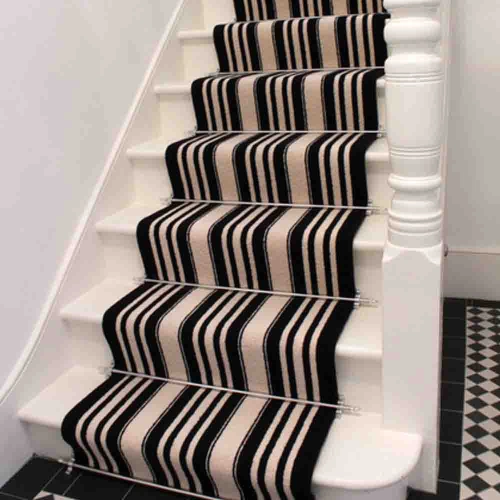 A black and white striped stair carpet runner on a white staircase with a white railing