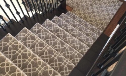 A geometric patterned stair carpet runner is installed on a carpeted