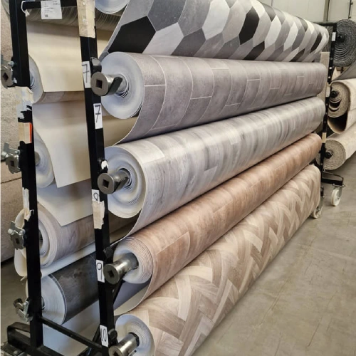 A rack of vinyl carpets rolls in various colors and patterns, displayed in a store